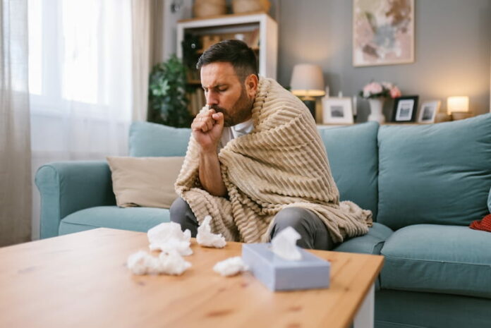 Ein kranker Mann sitzt auf dem Sofa und hat einen Karenztag