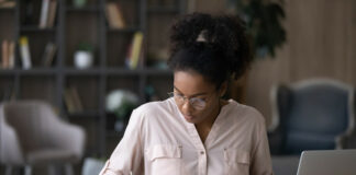 Wie viel kostet ein Studium? Studienkosten im Überblick Eine Studentin sitzt am Schreibtisch und berechnet ihre Studienkosten. Sie fragt sich "Wie viel kostet ein Studium?"