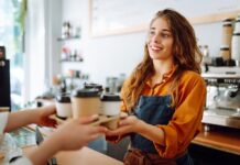 Schülerjobs: Dein Guide für den ersten Job Eine Schülerin steht im Rahmen ihres Schülerjobs im Café hinter der Theke. Sie verkauft Kaffee mit einem freundlichen Lächeln.