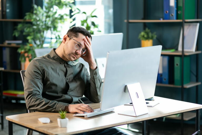 Ein man sitzt traurig vor dem Computer, an seinem Arbeitsplatz. Er wurde bei Beförderung übergangen.