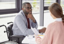 Aktives Zuhören: Warum es sich lohnt & wie es geht Ein Arbeitnehmer sitzt einer Kollegin gegenüber. Er zeigt aktives Zuhören während sie Statistiken vorstellt.