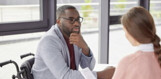 Aktives Zuhören: Warum es sich lohnt & wie es geht Ein Arbeitnehmer sitzt einer Kollegin gegenüber. Er zeigt aktives Zuhören während sie Statistiken vorstellt.