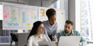 Ansoff-Matrix: Strategien für erfolgreiches Wachstum Ein Marketing-Team arbeitet am Laptop an einer Ansoff-Matrix. Im Hintergrund sieht man weitere Marketing-Methoden, wie ein Business Model Canvas.