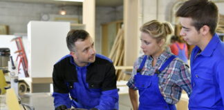 Jugendarbeitsschutzgesetz (JArbSchG): Deine Rechte als Azubi Zwei Auszubildende stehen vor einer Holzbearbeitungsmaschine und lassen sich von ihrem Berufsschullehrer die Funktion erklären. Als Azubis gilt für sie das Jugendarbeitsschutzgesetz.