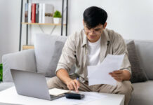 Werbungskosten: Dein Guide zur Steuererstattung – hol dir dein Geld zurück! Ein junger Arbeitnehmer sitzt vor seinem Laptop und gibt Werbungskosten bei seiner Steuererklärung an.