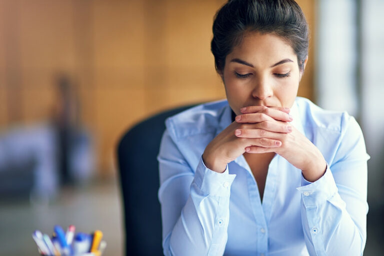 Eine Angestellte sitzt in Büro und sieht besorgt aus. Sie hat Zukunftsangst im Job.